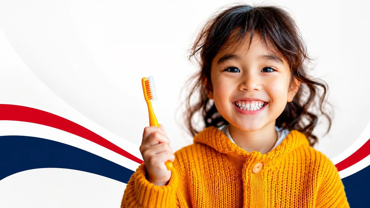 A smiling child holding a toothbrush at Lakewood Dental Group